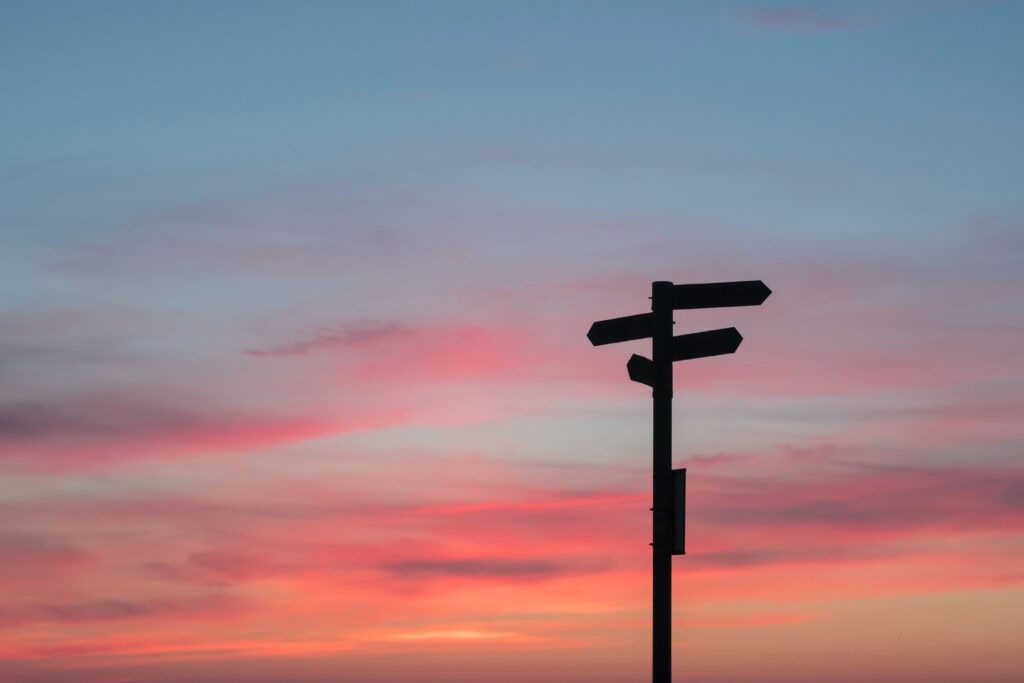a signpost with a sunset in the background